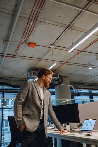 Smiling entrepreneur working with documents standing near desk in modern office © Kostiantyn