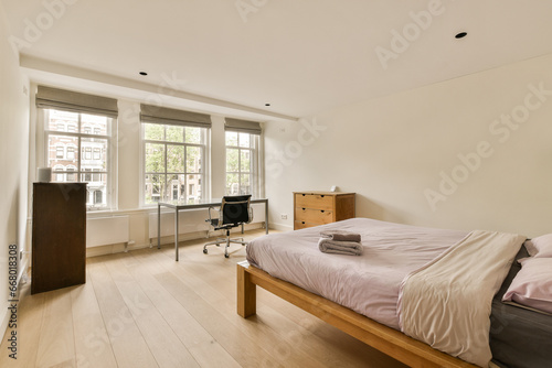 a bedroom with a bed, desk and tv in the corner of the room on the right is an open window