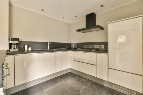 a modern kitchen with white cabinets and black counter tops in an apartment or residential area, taken from the side