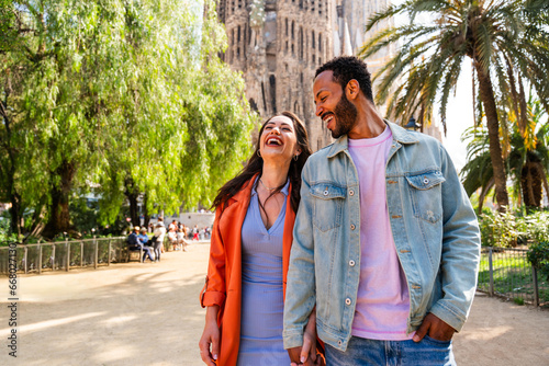 Multiracial beautiful happy couple of lovers dating at Sagrada Familia, Barcelona - Multiethnic tourists travelling in Europe and visiting a city in Spain, concepts about tourism and people lifestyle