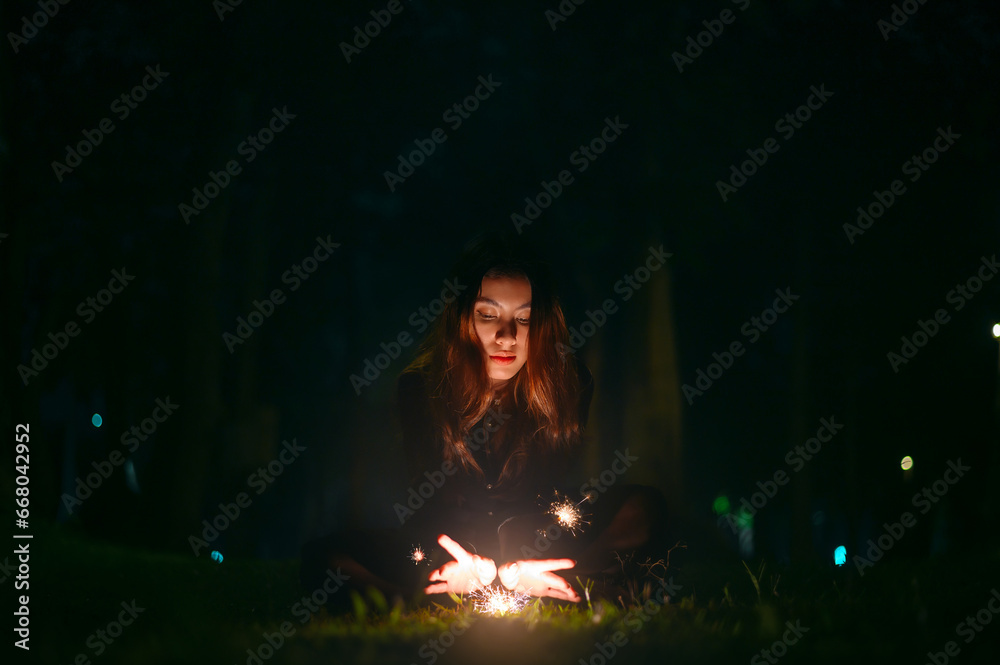 Portrait of beautiful witch in black dress with magic fire in forest at night Portrait of beautiful witch in black dress with magic fire in forest at night