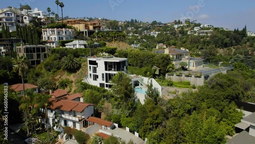 Aerial Backward Shot Of Houses Amidst Plants And Trees On Hills Against Sky - West Hollywood, California photo