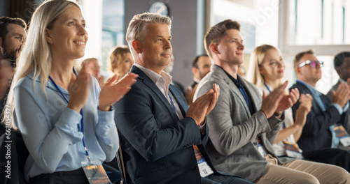 Male CEO Sitting in a Bright Crowded Auditorium at a Tech Conference. Confident Man Applauding After a Successful Keynote Presentation. Specialist Inspired by Latest Technological Advances.