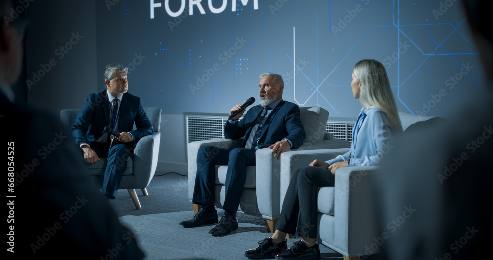 International Technology Conference: Host Asking Caucasian Male CEO a Question In Front Of Audience. Confident Man Delivering Inspirational Speech About Success And Diverse Attendees Listening. - obrazy, fototapety, plakaty 