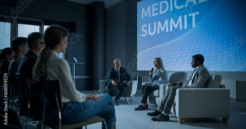 International Medical Summit: Host Asking Caucasian Female Pharmaceutical CEO a Question In Front Of Audience Of Diverse Attendees. Woman Talking About New Developments In Biotechnology, Medicine.