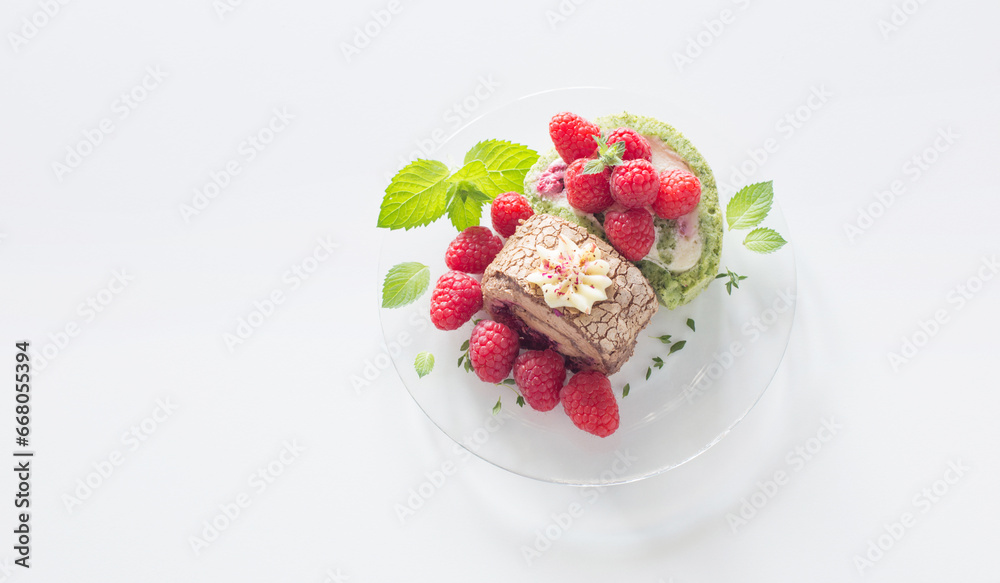 chocolate roll with raspberries and mint leaves on glass plate on  white table