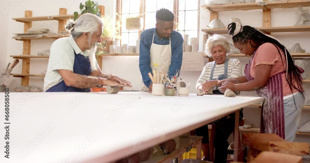 Happy diverse group of potters shaping clay with hands in pottery studio Happy diverse group of potters shaping clay with hands in pottery studio