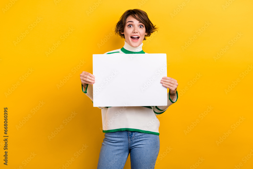 Photo of crazy promoter young girl hold paper poster placard advertise empty space information news blank isolated on yellow color background Photo of crazy promoter young girl hold paper poster placard advertise empty space information news blank isolated on yellow color background