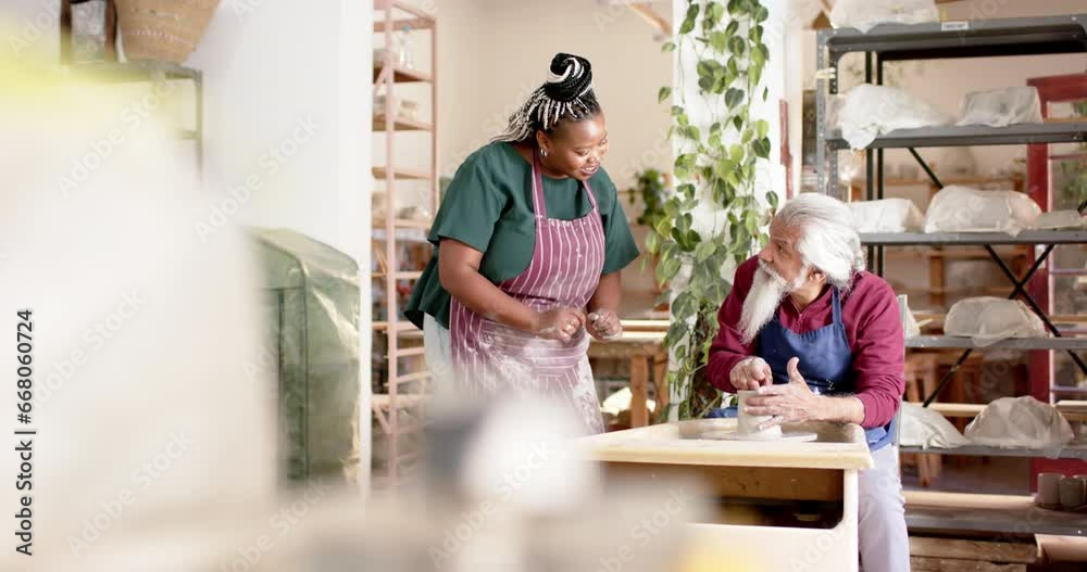 Focused diverse male and female potters using potter's wheel in pottery studio, slow motion Focused diverse male and female potters using potter's wheel in pottery studio, slow motion