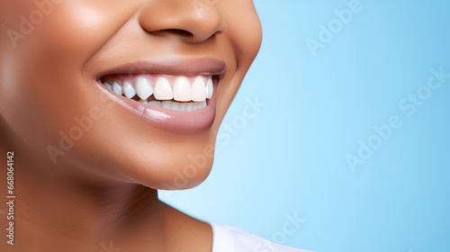 Close-up of a beautiful smiling African American woman with white perfect teeth isolated on a blue studio background with copy space. Dental care. Dentistry. Dentistry concept.