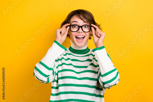 Photo of funny amazed girl try on vision specs can see everything OMG wear oversize pullover isolated yellow color background