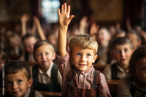 School children in classroom at lesson raising their hands