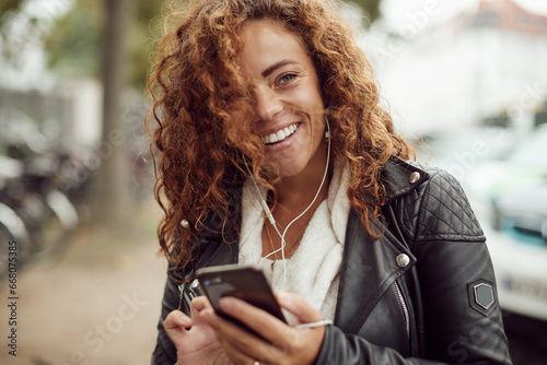 Laughing young woman talking on her cellphone in the city photo