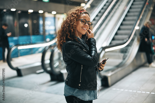 Smiling woman listening to music on a metro station platform photo