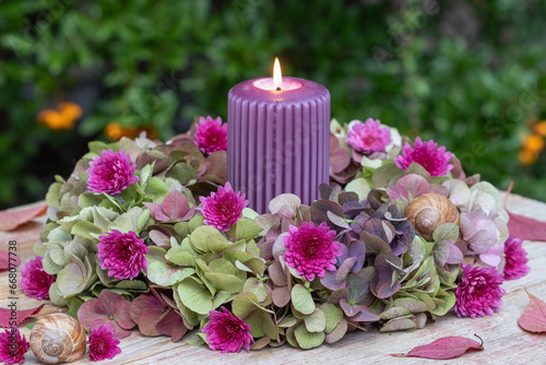 Arrangement mit einer Kerze und Blumenkranz mit Hortensienblüten und Chrysanthemen