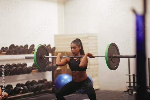 Muscular young woman strength training with weights at a gym