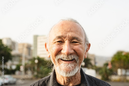 Happy senior man smiling in front of camera in the city - Elderly people lifestyle concept photo