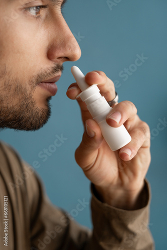 Close-up of young arabic man spraying drops in nose.