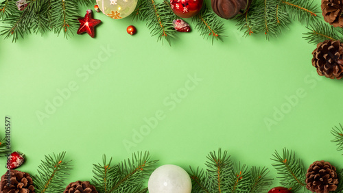 Green colored background with paper texturea above, Christmas decorations and branches of the Christmas tree