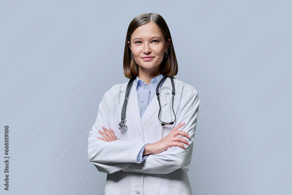Portrait of young woman doctor student intern in white coat on grey background Portrait of young woman doctor student intern in white coat on grey background