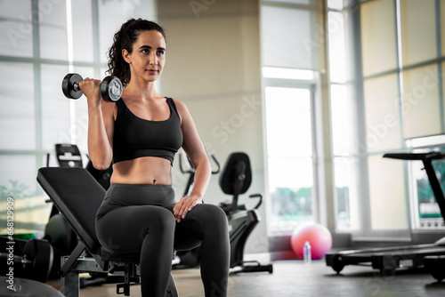 Woman exercising in the gym By lifting weights to tighten your arm muscles.