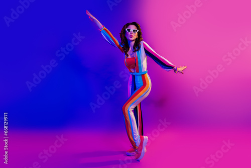 Full body portrait of carefree lovely lady wear striped costume dancing clubbing isolated on bright neon background