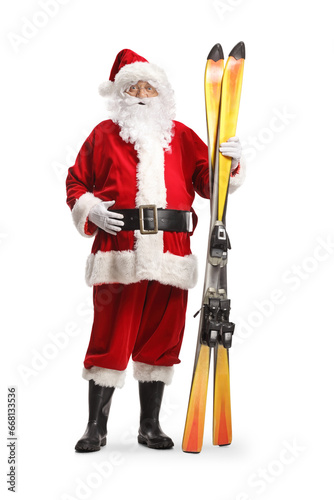 Full length portrait of Santa Claus holding a pair of skis