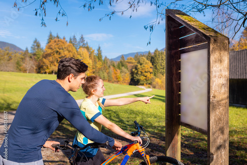 Cyclist woman and man looking at information board in nature photo