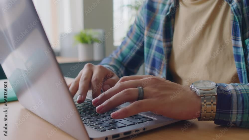 Cropped shot of unrecognizable male student wearing blue checkered shirt typing on laptop in class Cropped shot of unrecognizable male student wearing blue checkered shirt typing on laptop in class