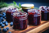Close up of blueberry jam in jar in background of green nature. Meal concept of food and cooking.