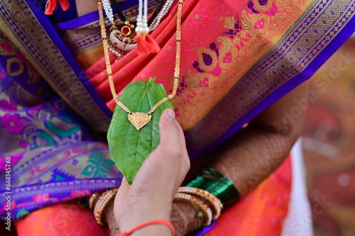 Golden Mangalsutra on green leaf. Married Woman Golden Chain. Indian Wedding Necklace. Maharashtra Culture. Maharashtra Wedding Elements. Holding chain	