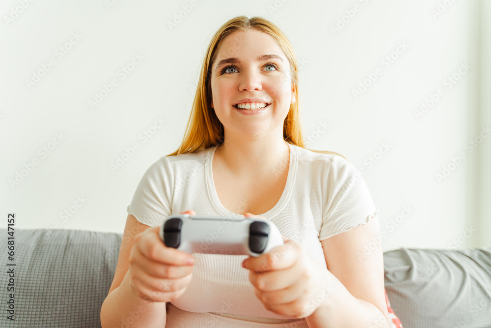 Portrait of attractive woman playing video game, holding joystick, sitting on comfortable sofa Portrait of attractive woman playing video game, holding joystick, sitting on comfortable sofa