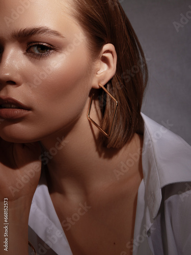 A lovely model with gold rings, earrings, and a bracelet. Jewelry shop. Fashion, Beauty . Portrait of a beautiful young woman with jewellery. Stylish brunette model with natural beauty and long hair