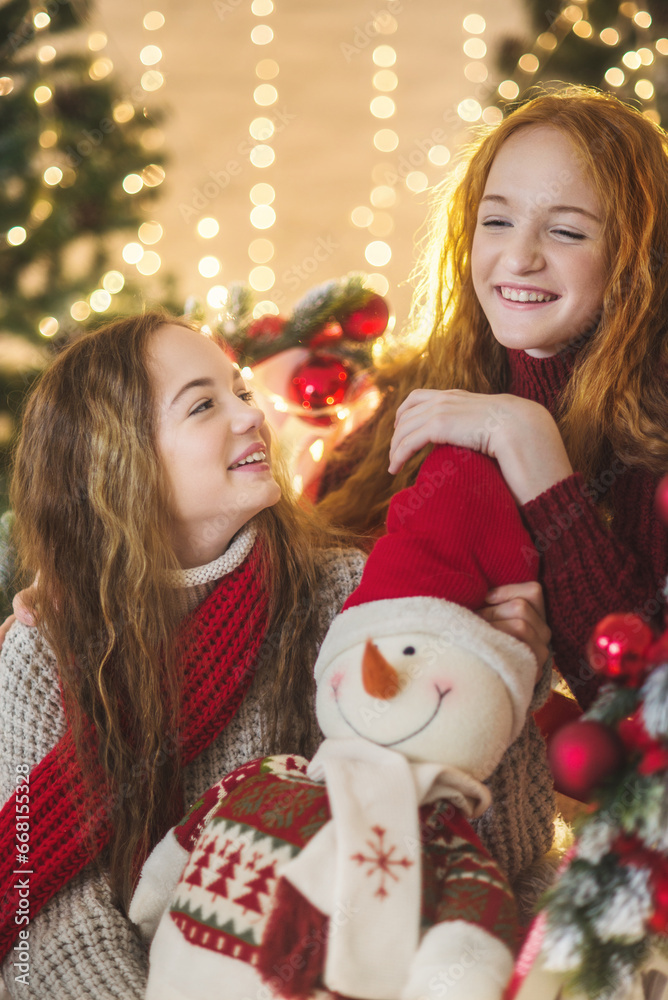 Two teenagers girls in christmas decorations. New year lights garlands. Christmas card with two pretty girls