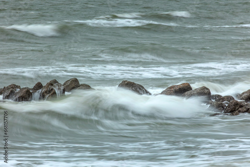 Long exposure shot of the sea showing movement of water over rocks and waves splashing, smooth silky water, rocks stationary, water moving