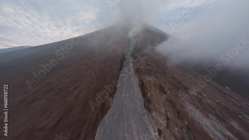 Drone raising active volcanic crater summit natural gas stream danger heat extreme. Aerial morning view approaching eruption volcano peak smoke falling stones disaster eructation explosion landscape