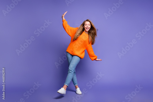 Full length shot of young teenager girl dancing wear orange pullover with jeans to halloween nightclub isolated on purple color background