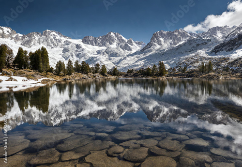 Crystal clear lake reflecting snow capped Sierra Nevada mountains.