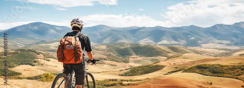 Tourist on a bicycle stopped to look at the beautiful view of the mountains and valley. A cyclist with a backpack against the backdrop of a beautiful landscape with hills and blue sky. Generative AI
