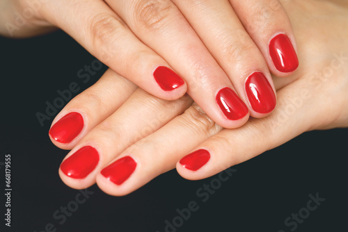 Beautiful female hand painting acrylic gel red nails. Fashion style.