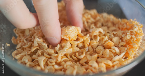 Tablou pe pânză Man picks up last whole large popcorn among husks of corn in plate