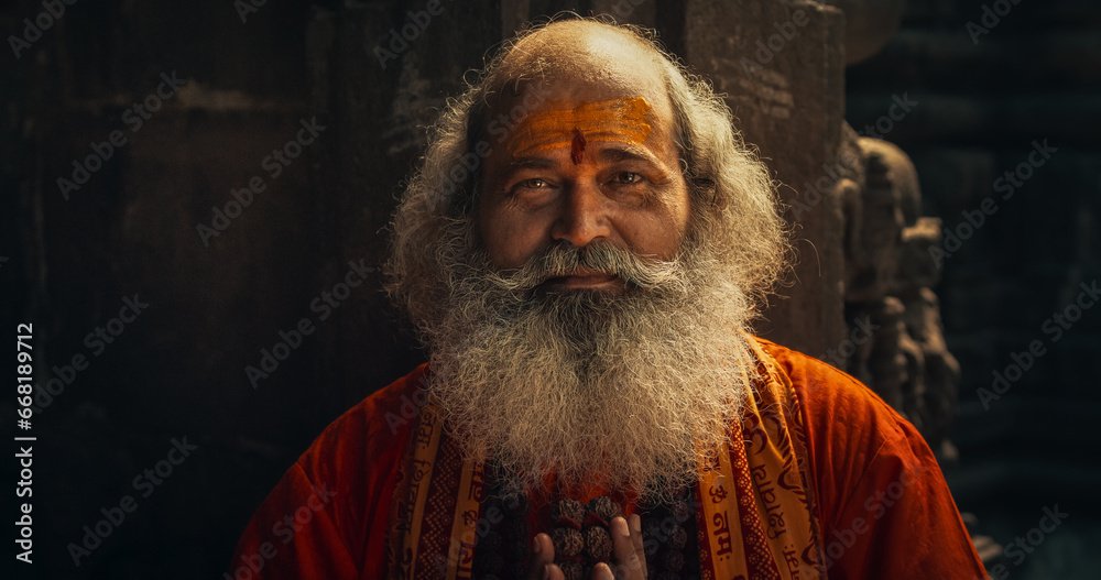 Portrait of a Senior Hindu Monk Looking at the Camera and Smiling in an Ancient Temple. Friendly Indian Senior Man Posing as he is seeking Guidance and Wisdom from his Religion