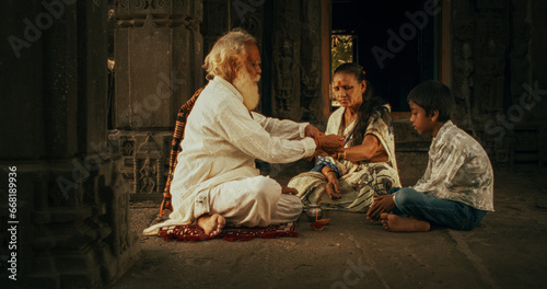 Authentic Footage of Hindu Priest Tying a Mauli Thread Around a Female Temple Follower's Wrist. Small Family Visiting Their Senior Guru, Faithful Worshipers in Religious Ceremony and Ritual