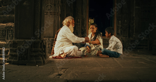 Authentic Footage of Hindu Priest Tying a Mauli Thread Around a Female Temple Follower's Wrist. Small Family Visiting Their Senior Guru, Faithful Worshipers in Religious Ceremony and Ritual