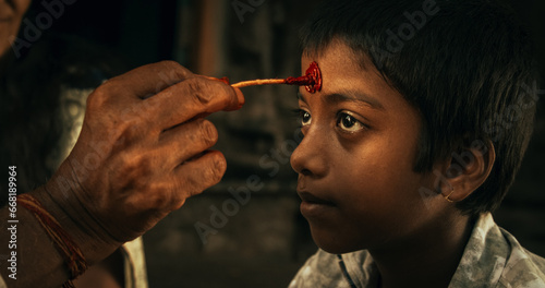 Authentic Footage of Hindu Priest Putting a Tilaka on Male Kid in a Temple. Senior Guru Giving Blessings with a Mark on the Forehead to a Child, Faithful Worshipers in Religious Ceremony photo