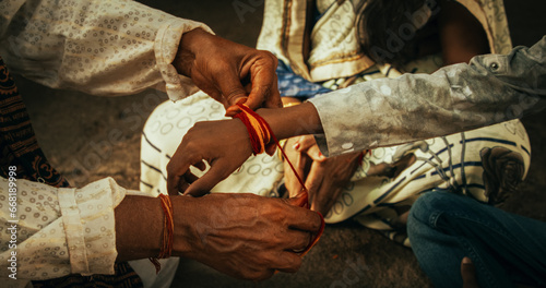 Close Up Authentic Footage of Hindu Priest Tying a Mauli Thread Around a Male Kid's Wrist in a Temple. Small Family Visiting Their Senior Guru, Seeking Guidance. Family Elder Passing on Wisdom