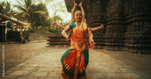 Portrait of Indian Women in Traditional Clothes Dancing Bharatanatyam in Colourful Sari. Three Expressive Young Females Performing Folk Dance Choreography in an Ancient Temple photo