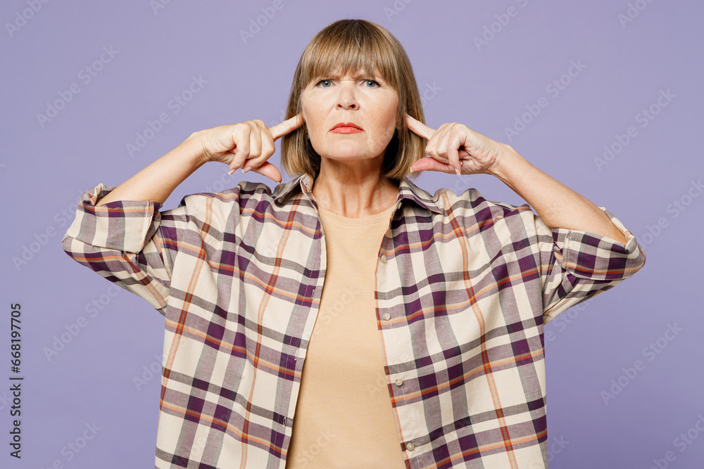 Elderly gray-haired woman 50s years old wear beige t-shirt shirt casual clothes cover ears with hands fingers do not want to listen scream isolated on plain light purple background. Lifestyle concept. Elderly gray-haired woman 50s years old wear beige t-shirt shirt casual clothes cover ears with hands fingers do not want to listen scream isolated on plain light purple background. Lifestyle concept.