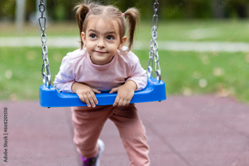 Cute little girl on swing in public park. Cute little girl on swing in public park.