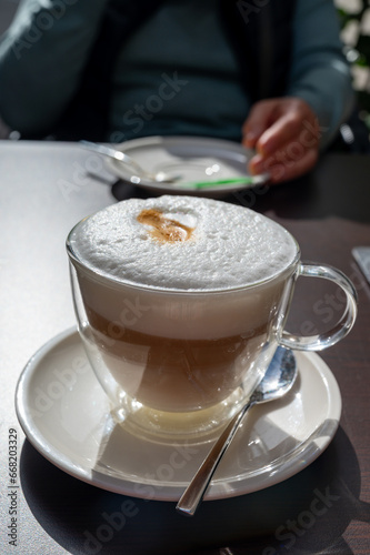 Fototapeta Naklejka Na Ścianę i Meble -  Drinking tasty fresh brewed Italian caffe latte coffee with whipped milk in outdoor cafe